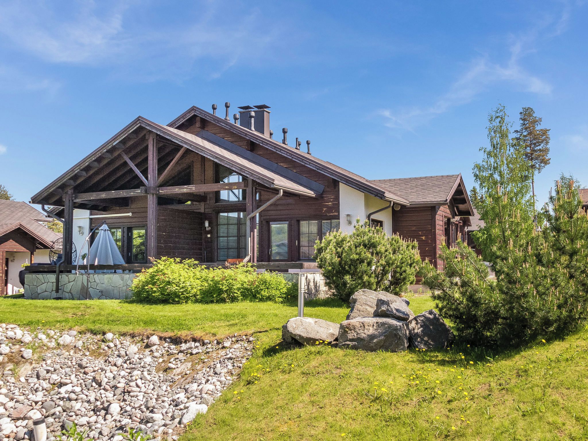 A modern house with a sloped roof, large windows, and a stone foundation.