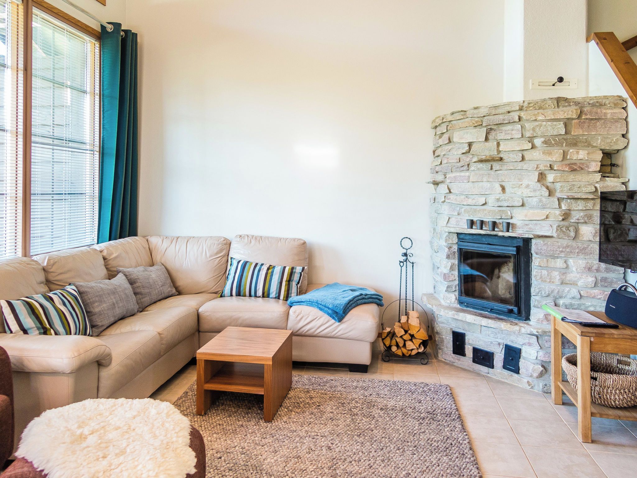 Una sala de estar con chimenea de piedra, un sofá color beige, una mesa de centro y una alfombra.