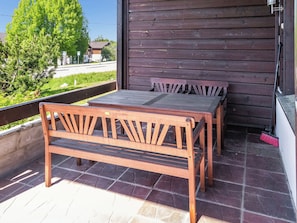 A wooden bench and table set on a tiled patio with a view of a road and greenery. - Pike 2 as. 1 by Interhome (Nilsiä)