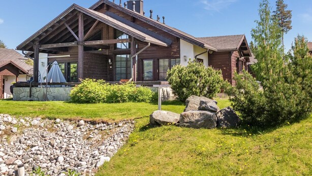 A modern house with a large porch, stone foundation, and a well-maintained garden with rocks and shrubs. - Pike 2 as. 1 by Interhome (Nilsiä)