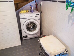 A compact laundry area with a front-loading washing machine, a drying rack, and a small storage cabinet. - Pike 2 as. 1 by Interhome (Nilsiä)