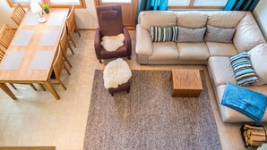 A living room with a sofa, armchair, coffee table, and dining table with chairs. - Pike 2 as. 1 by Interhome (Nilsiä)