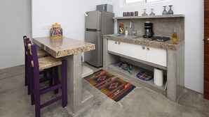 Een compacte keuken met een koelkast, een wastafel en een klein aanrecht.