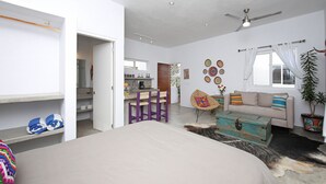 Een slaapkamer met een bed, een bank, een salontafel en een eethoek met stoelen.
