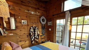 Una stanza accogliente in legno con un ampio letto, una lampada a sospensione e vista all'esterno tramite una finestra.