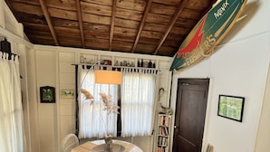 Una stanza accogliente con soffitto in legno, un tavolo da pranzo con sedie, una libreria e un cartello appeso al muro.