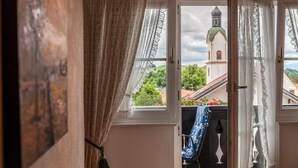 Ein offenes Fenster mit Blick auf eine Kirche und Grünflächen.