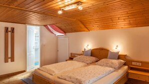 Eine Holzbalkendecke, ein Bett mit zwei Kissen, ein Nachttisch und eine Tür zu einem Badezimmer.
