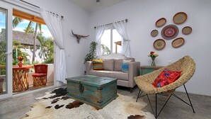A room with a sofa, a wicker chair, a wooden chest, and a cowhide rug. - Peace amid the Palms at La Isla Bonita Villa 2 (Sayulita)