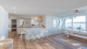 Una cocina moderna con una isla grande, taburetes de bar y vista al agua.