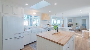 Una cocina moderna con armarios blancos, una isla de madera y un tragaluz.