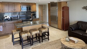 Une cuisine moderne avec des meubles en bois, un réfrigérateur en acier inoxydable et un îlot central doté de tabourets de bar.