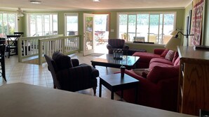 Un vaste espace de vie doté d’une grande fenêtre, d’un balcon et d’un coin salon comprenant un canapé et des fauteuils.