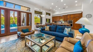 Amplia sala de estar con una mesa de centro de vidrio, sofás de cuero y vista al patio exterior.