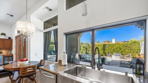 Una cocina moderna con una isla grande, pileta de acero inoxidable y un comedor con sillas de madera.