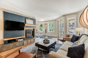 A modern living room with a flat-screen TV, fireplace, comfortable seating, and large windows. - Walk to Mtn/Free Town Bus-Pool-HotTub-Gym-Grill (Steamboat Springs)