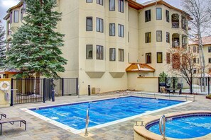 A swimming pool with a tiled edge, surrounded by a stone patio.