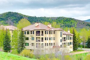 A multi-story residential building with balconies, surrounded by greenery and mountains. - Walk to Mtn/Free Town Bus-Pool-HotTub-Gym-Grill (Steamboat Springs)