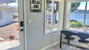 Ein Zimmer mit Seeblick, eine Essecke mit Stühlen, ein Teppich und ein Schild an der Wand mit der Aufschrift 'RELAX AND UNWIND'.