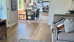 Ein geräumiger Wohnbereich mit einer Couch, einem Esstisch mit Stühlen und einer Küche im Hintergrund.