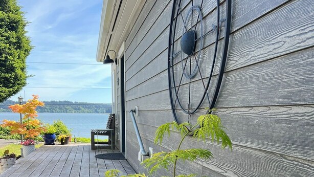 Ein Holzdeck mit einem Blumentopf und einer Bank, mit Blick auf ein Gewässer.