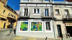 Ein Gebäude mit einer grauen Fassade, zwei Fenstern im Erdgeschoss und einem Balkon.
