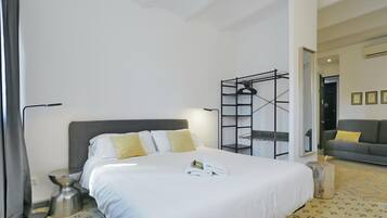 Una habitación de hotel con cama, mesita de noche, lámpara, armario y espejo.