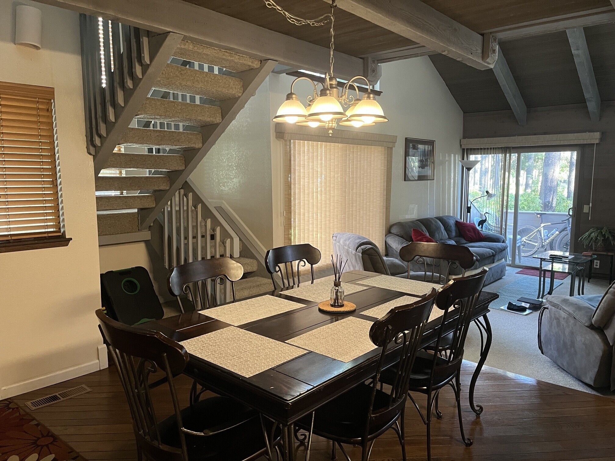 A dining area with a wooden table, chairs, and a chandelier.