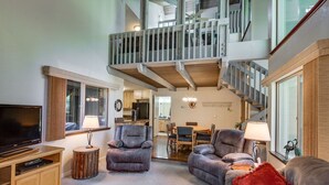 A spacious living area with a high ceiling, a wooden staircase, and a dining area. - Sunriver Family Escape with 6 SHARC Passes (Sunriver)