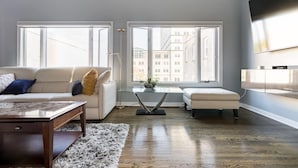 A modern living room with a sofa, a coffee table, and a glass-top table with a plant.