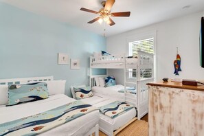 Una habitación con literas, ventilador de techo y ventana con persianas.