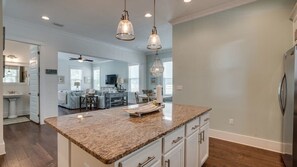Una cocina moderna con encimeras de granito, armarios blancos e iluminación colgante.