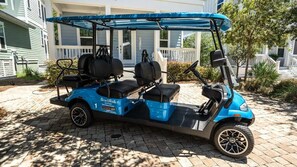 Un véhicule de golf bleu est garé sur une allée pavée.