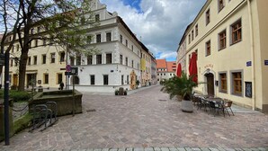 A cobblestone street with historic buildings, outdoor seating, and a fountain. - Fantastic apartment in a prime location near Dresden at the gateway to Saxon Switzerland (Pirna)
