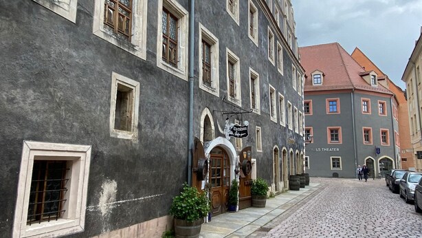 A cobblestone street lined with historic buildings, including a theater and a restaurant. - Fantastic apartment in a prime location near Dresden at the gateway to Saxon Switzerland (Pirna)