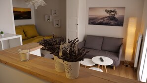 A modern living room with a wooden coffee table, a sofa, and a small white table with a remote control. There are two potted plants on the coffee table. - Fantastic apartment in a prime location near Dresden at the gateway to Saxon Switzerland (Pirna)
