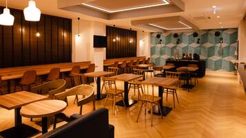 Un restaurante moderno con mesas y sillas de madera, una zona de bar y una pared con diseño.