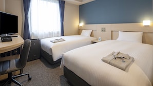 Ett hotellrum med två sängar, ett skrivbord med en dator och en stol.