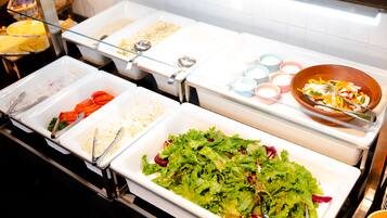 Un bufé con diversos alimentos, entre ellos ensaladas, verduras y salsas.
