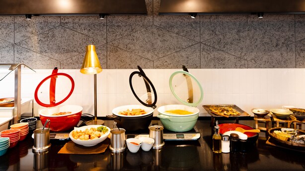 En buffé med olika rätter, skålar och serveringsredskap uppställda på en avställningsyta.