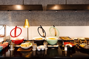 A buffet setup with various dishes, bowls, and serving utensils on a counter. - Jr Clement Inn Imabari (Imabari)