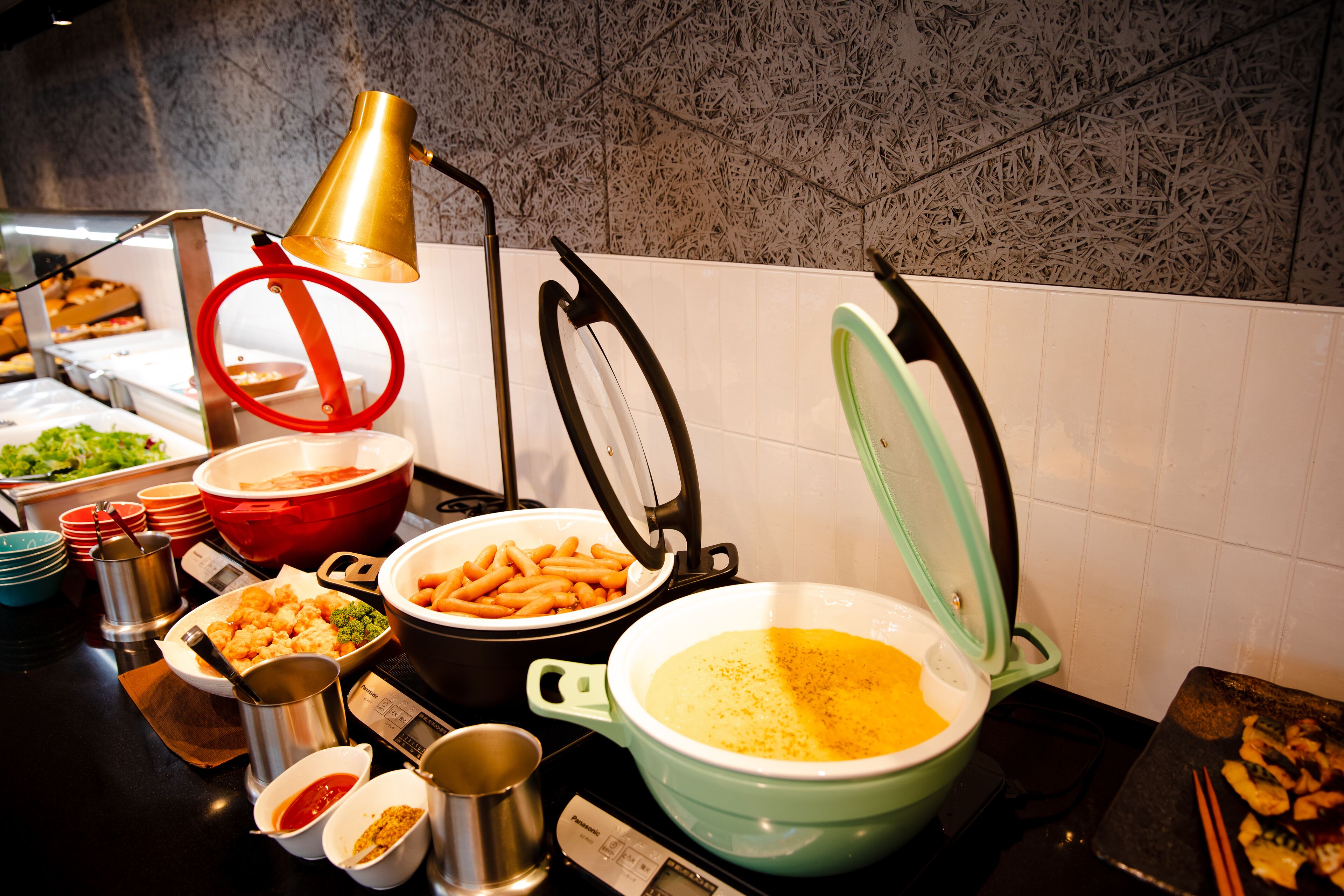 A buffet with various dishes and cooking equipment.