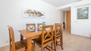 Un comedor con una mesa y sillas de madera, un florero y dos cuadros en las paredes.