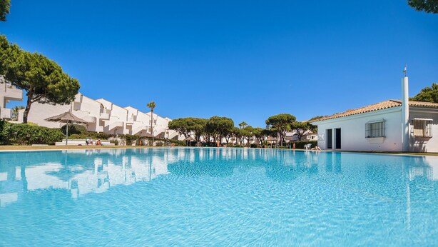 A clear swimming pool with a white building in the background.