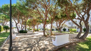A courtyard with trees, a white bench, and a lamp post.