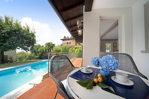A poolside area with a table, chairs, and a view of a building in the background.