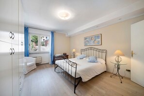 Une chambre à coucher avec un lit, des tables de chevet, une armoire et une fenêtre avec des rideaux.
