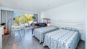 Een moderne hotelkamer met balkon, bureau, twee bedden en uitzicht op een bergachtig landschap.