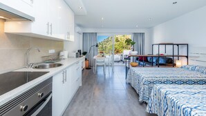 Een moderne hotelkamer met een keuken, een zithoek en een bed met beddengoed met een patroon.