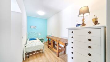 A bedroom with a bed, a wooden desk, a dresser, and a lamp.